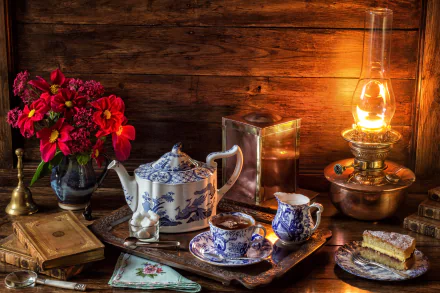 A 4K Ultra HD still life wallpaper featuring a blue and white teapot and teacups, cake slices, a vintage lantern, a book, and vibrant flowers on a wooden table.