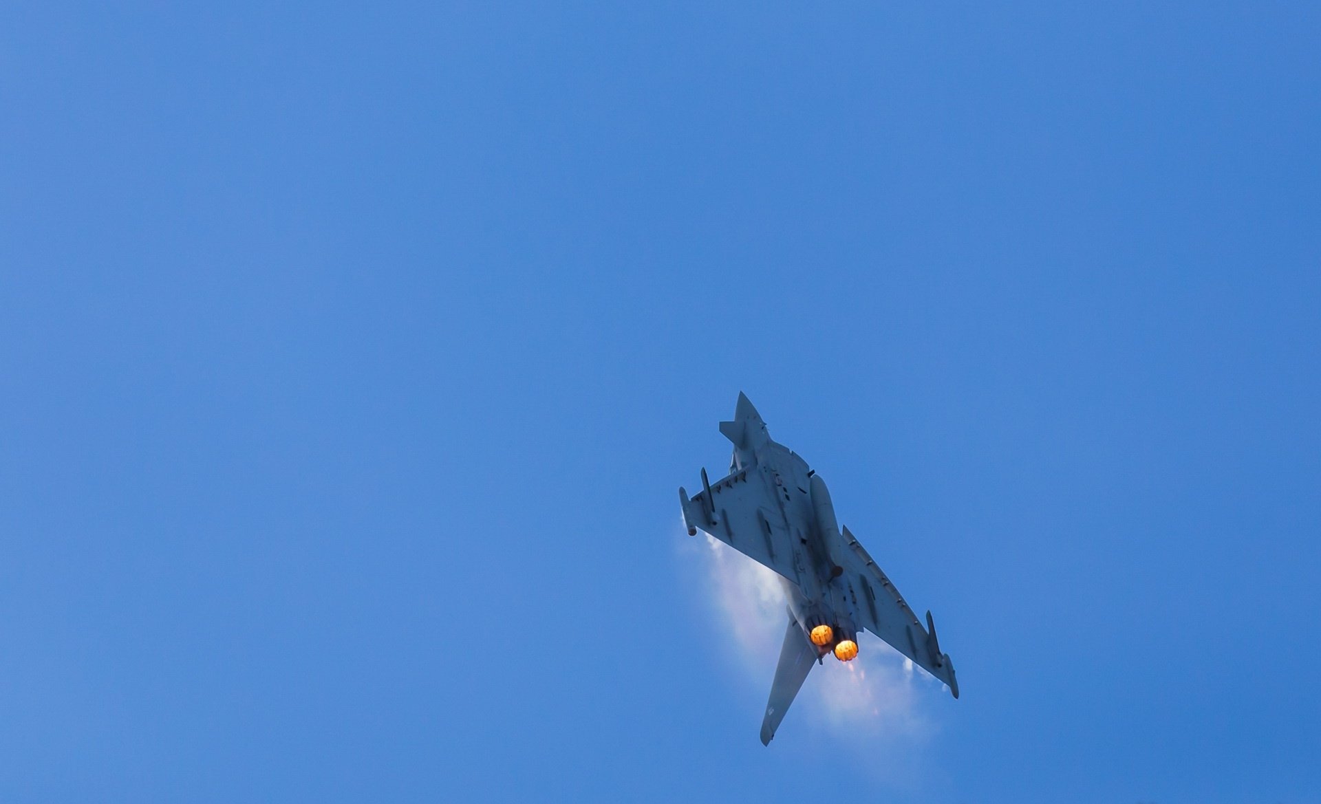 HD desktop wallpaper featuring a Eurofighter Typhoon jet fighter warplane soaring against a clear blue sky, showcasing military aircraft in dynamic flight.