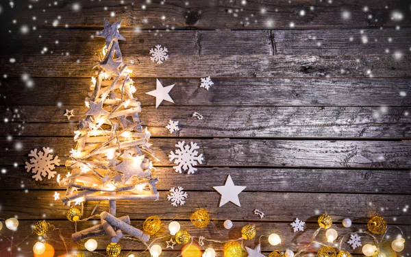 A festive HD desktop wallpaper featuring a rustic wooden background with a Christmas tree made of lights and paper stars, snowflakes, and holiday ornaments.