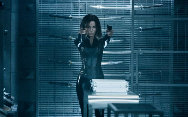 HD desktop wallpaper of Selene, portrayed by Kate Beckinsale in Underworld: Blood Wars, standing in a room with weapons, aiming pistols forward.