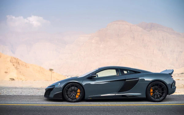 Silver McLaren 675LT supercar parked on a desert road with mountains in the background, showcased as an HD PC desktop wallpaper and background.