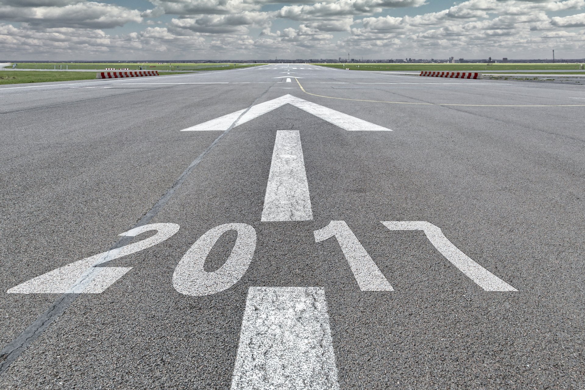 A clear road with a large white arrow and 2017 painted on the asphalt, stretching toward the horizon under a cloudy sky, symbolizing the New Year holiday.