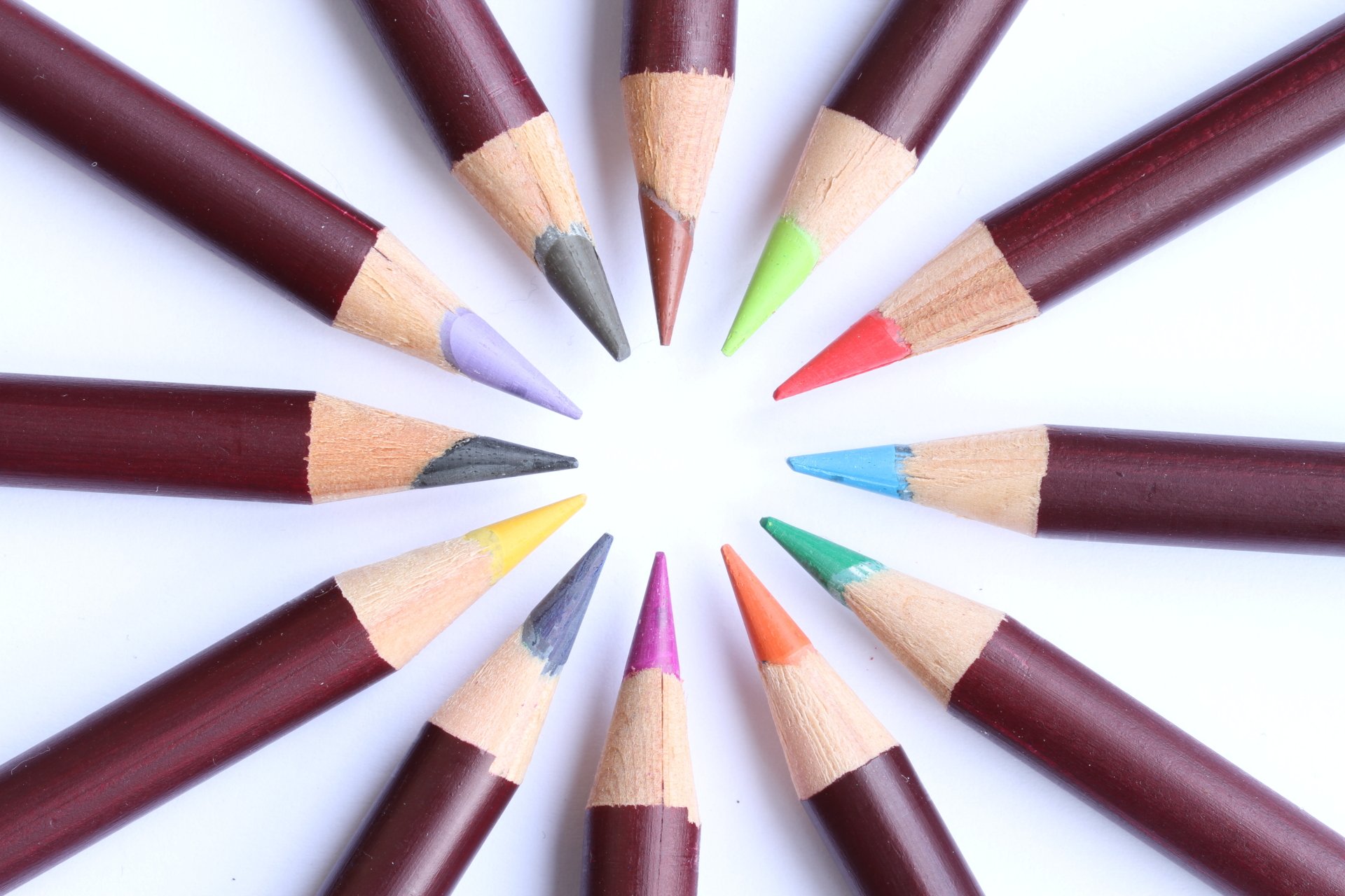 Sharpened colored pencils arranged in a radial circle on white background — color photography presented as a 5K Ultra HD PC desktop wallpaper and background.