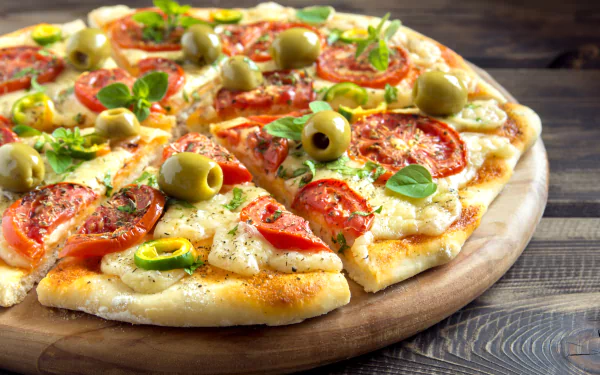 A close-up 4K Ultra HD desktop wallpaper of a freshly baked pizza topped with tomatoes, green olives, basil, and melted cheese on a wooden board.