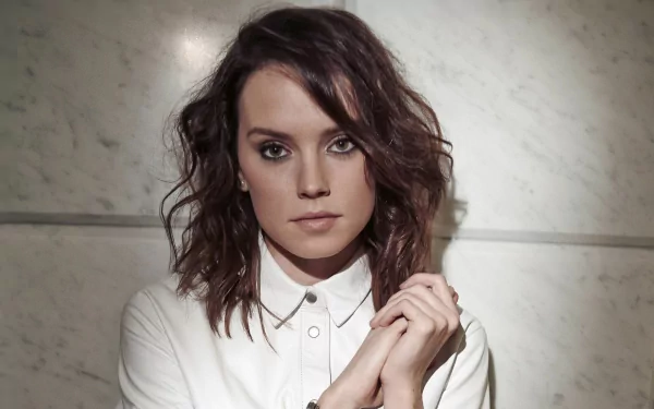 HD desktop wallpaper featuring celebrity Daisy Ridley with wavy hair, wearing a white button-up shirt, set against a neutral marble background.