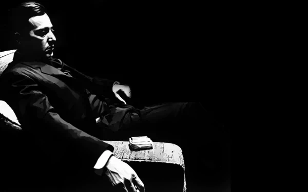 HD PC desktop wallpaper from The Godfather: Part II — stark black-and-white of a brooding man seated in shadow, hand resting near a small stack of cash.
