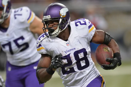 HD desktop wallpaper featuring a focused football player in a purple and gold uniform, number 28, carrying the ball mid-game.