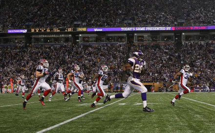 HD wallpaper of a football player in purple and gold running with the ball during a game, with a crowd in the background.