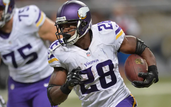 HD desktop wallpaper featuring a focused football player in a purple and gold uniform, number 28, carrying the ball mid-game.