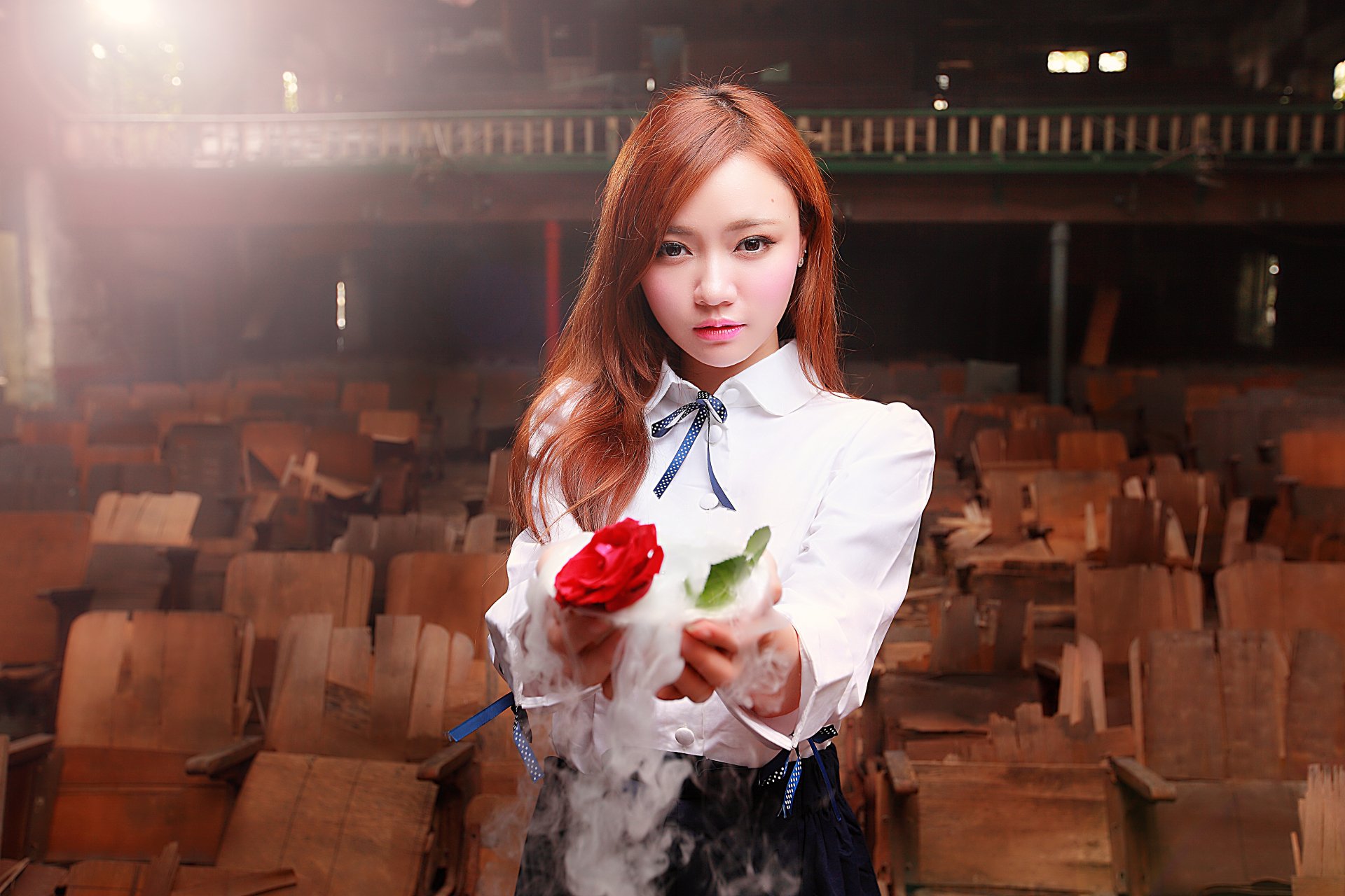 A red-haired model with brown eyes holds a red rose against a blurred background. The image is high definition and set as a desktop wallpaper.