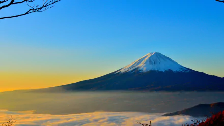 HD desktop wallpaper featuring Mount Fuji in Japan, with its snow-capped peak rising above clouds under a clear blue sky, capturing the serene beauty of the mountain and nature.