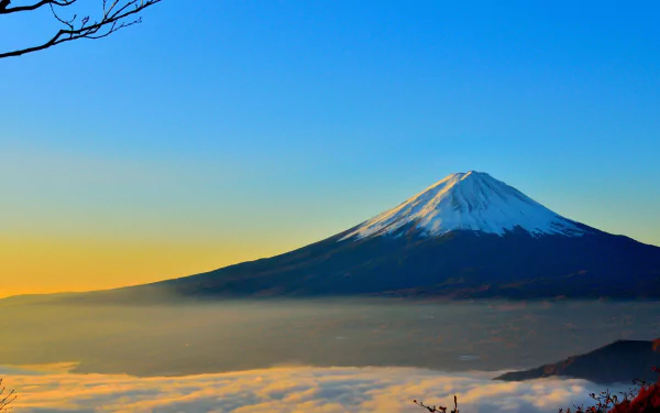 HD desktop wallpaper featuring Mount Fuji in Japan, with its snow-capped peak rising above clouds under a clear blue sky, capturing the serene beauty of the mountain and nature.
