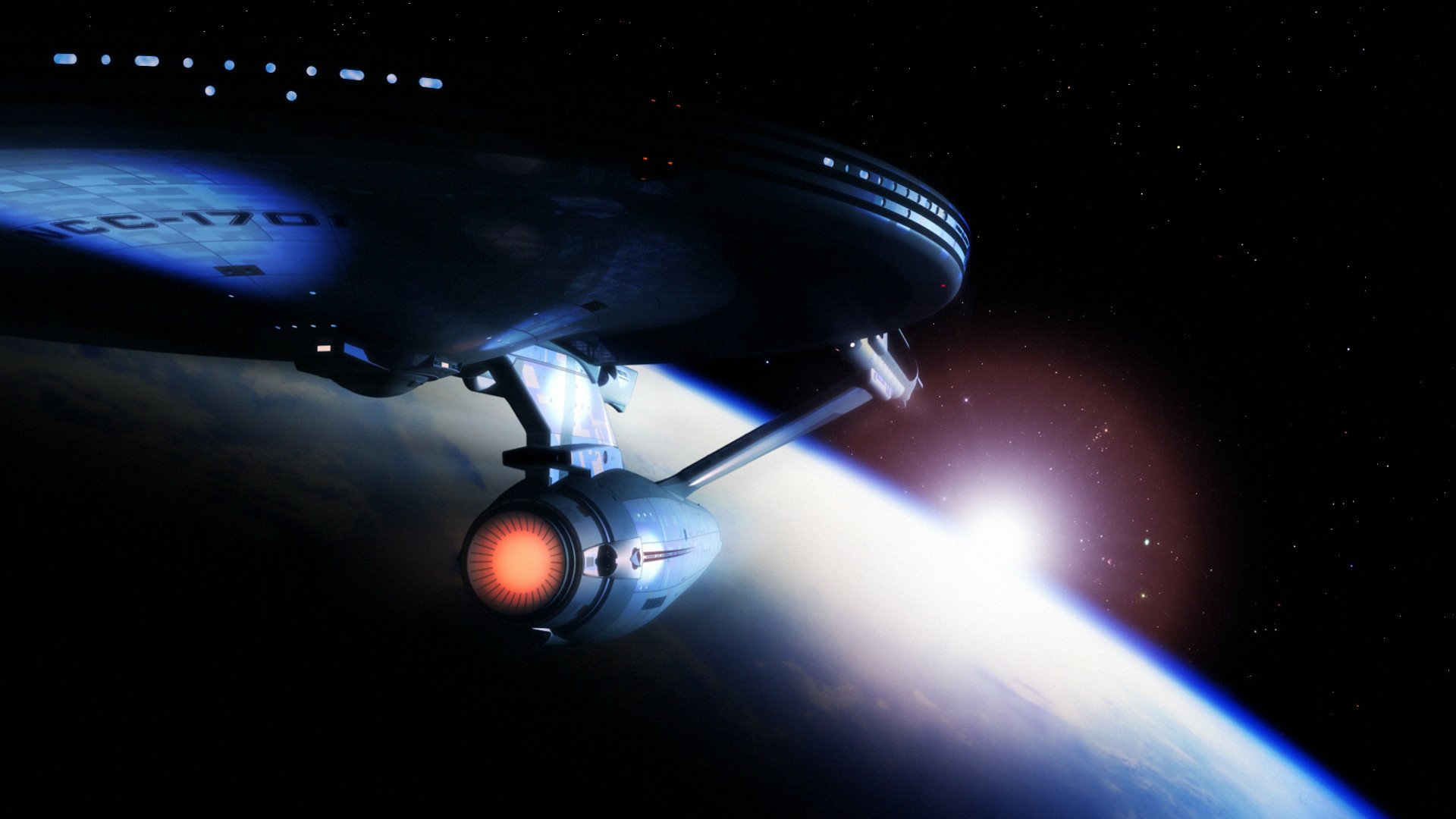HD PC desktop wallpaper of the USS Enterprise from the movie Star Trek: The Motion Picture, gliding above a planet with glowing warp nacelles and a distant starfield.