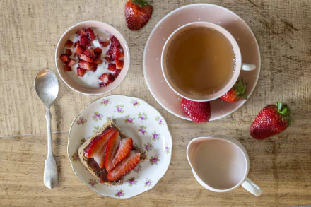 HD desktop wallpaper of a breakfast spread: cup of tea, bowl of yogurt with diced strawberries, toast topped with sliced strawberries on a floral plate and a milk jug.