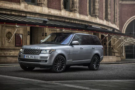 HD desktop wallpaper featuring a silver Land Rover Range Rover SUV parked on a city street with an architectural building in the background.