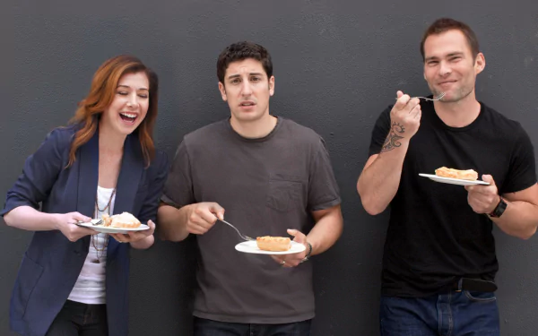 HD PC desktop wallpaper: three characters from the movie American Reunion laugh while eating slices of cake against a plain gray wall.