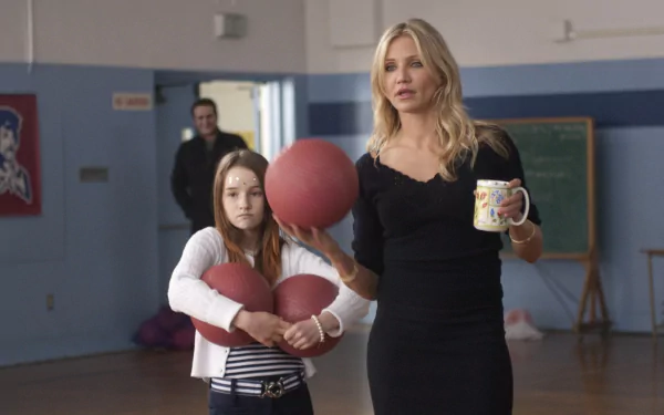 Cameron Diaz holding a mug and a dodgeball in a gymnasium scene from the movie Bad Teacher, featured as an HD PC desktop wallpaper.