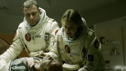 Scene from the movie The Last Days On Mars showing two astronauts in white suits attending to a fallen comrade, captured as an HD PC desktop wallpaper background.