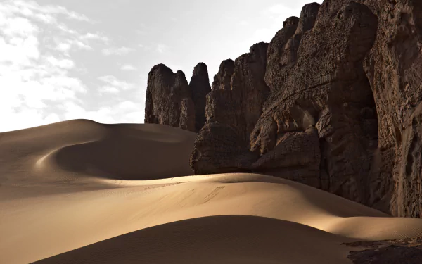 Sunlit sand dunes and rugged rock formations of Tassili N'Ajjer National Park in the Sahara Desert, Algeria, captured in a stunning 4K Ultra HD landscape.
