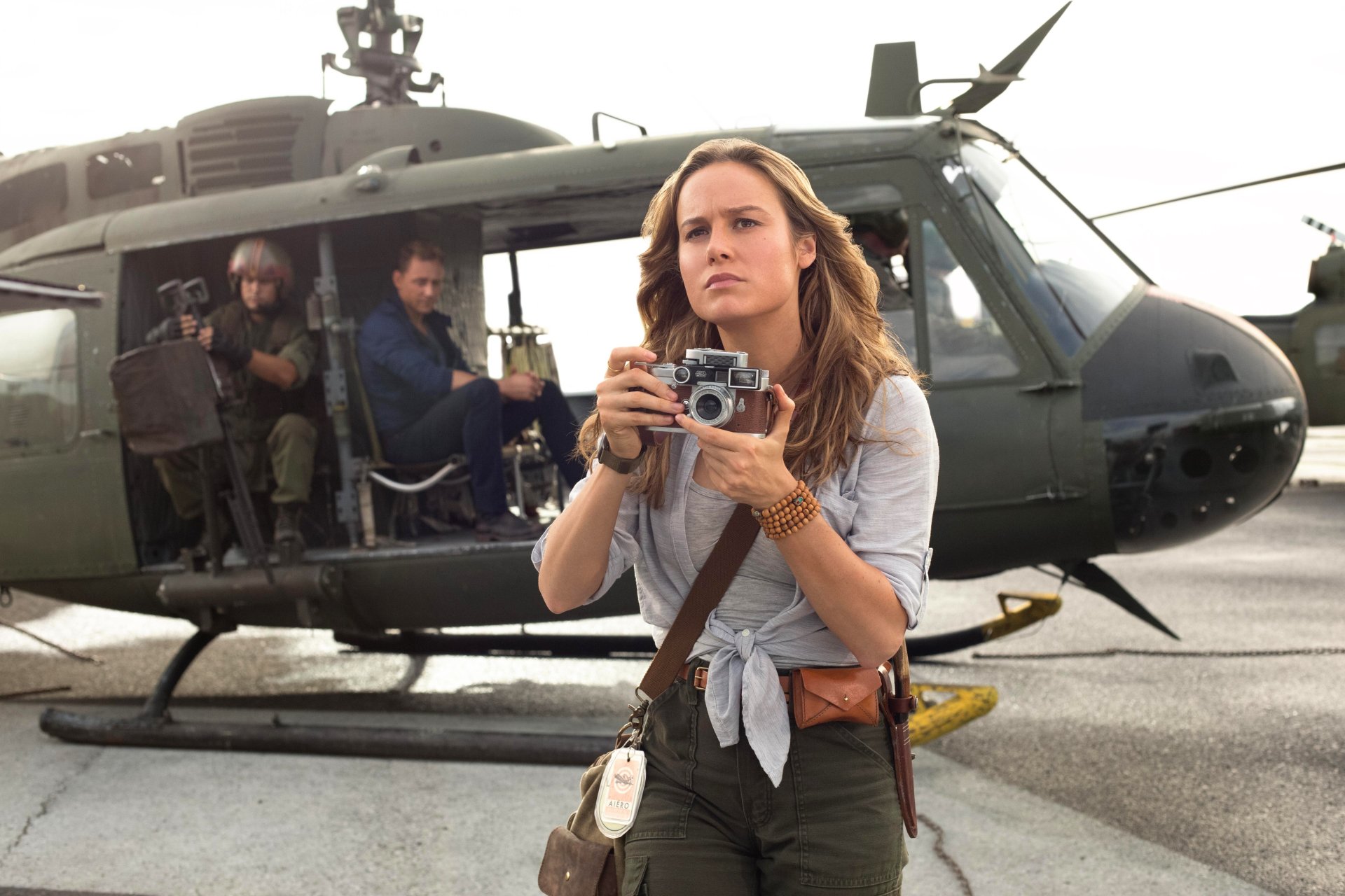 HD desktop wallpaper and background featuring Brie Larson holding a camera, with a military helicopter and crew in the scene from the movie Kong: Skull Island.