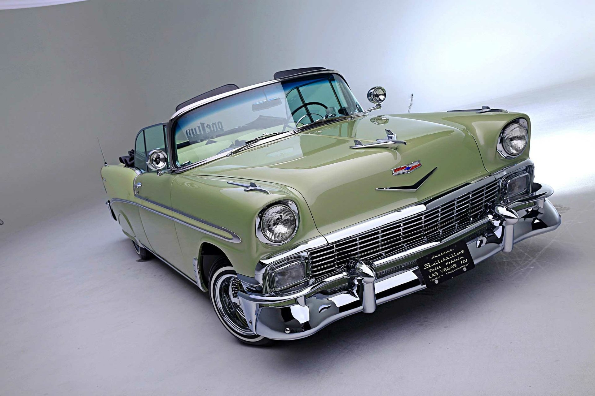 HD desktop wallpaper featuring a green Chevrolet Bel Air lowrider with chrome details against a simple light background.