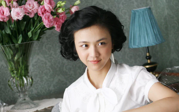 A scene from the movie Lust, Caution, featuring a woman with short black hair and a white blouse, used as an HD desktop wallpaper and background. In the background, there's a vase with pink flowers and a blue lamp.