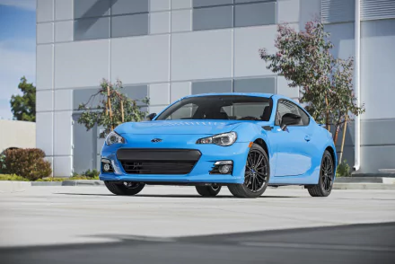 HD desktop wallpaper of a vibrant blue Subaru BRZ parked in front of a modern building, showcasing the car's sleek design and urban setting.