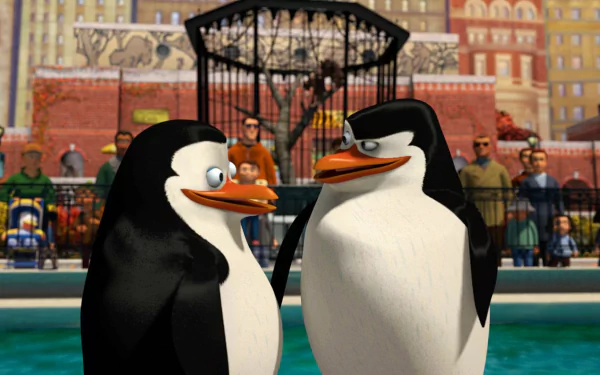 HD desktop wallpaper featuring two penguins from the movie Madagascar, with a zoo background and cityscape.