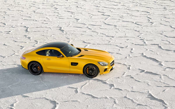 Yellow Mercedes-Benz AMG GT sports car parked on a textured white salt flat, captured in vibrant 4K Ultra HD for a striking PC desktop wallpaper.