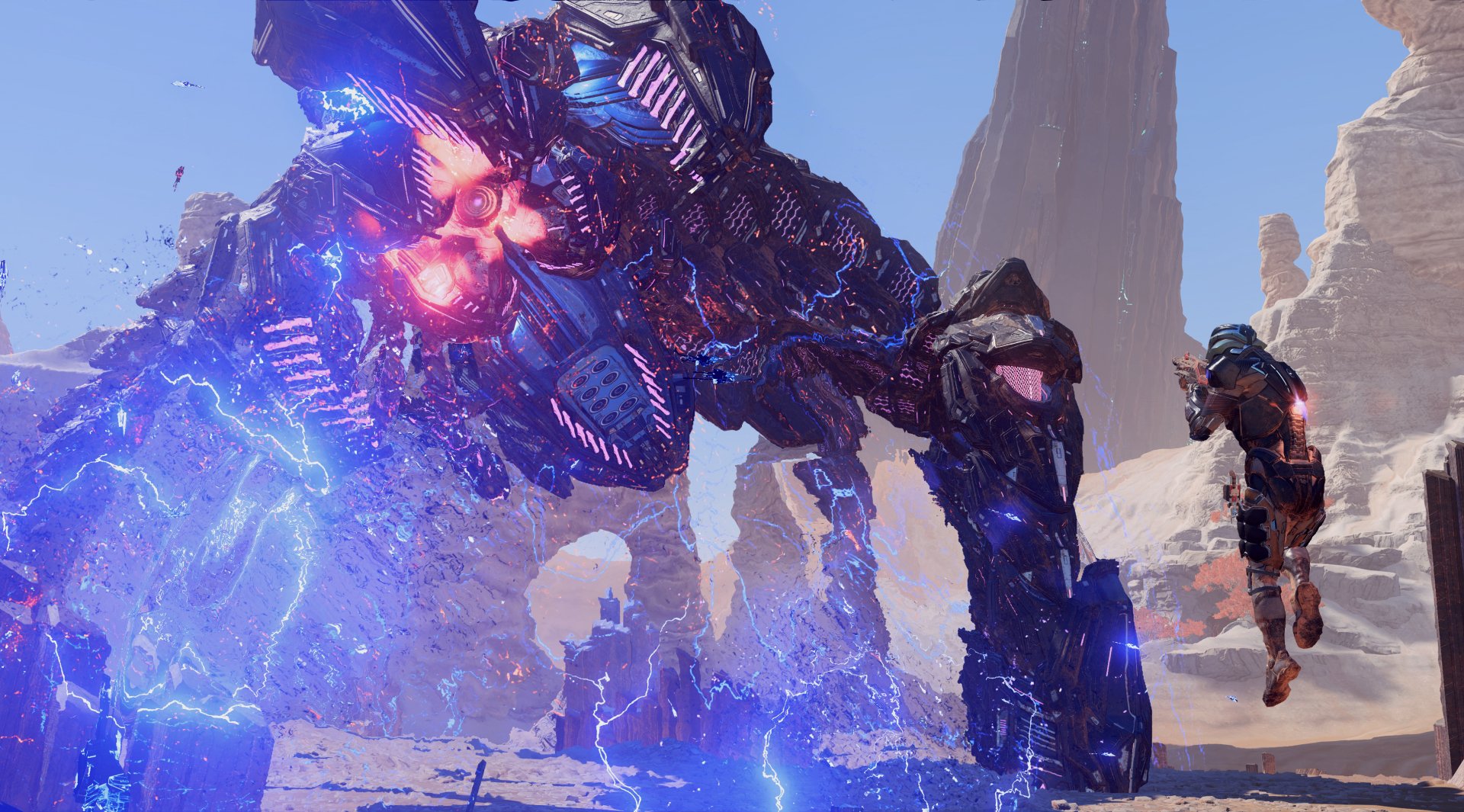 An HD desktop wallpaper from Mass Effect: Andromeda featuring an intense battle scene with a character confronting a towering, glowing mechanical creature in a rocky desert landscape.