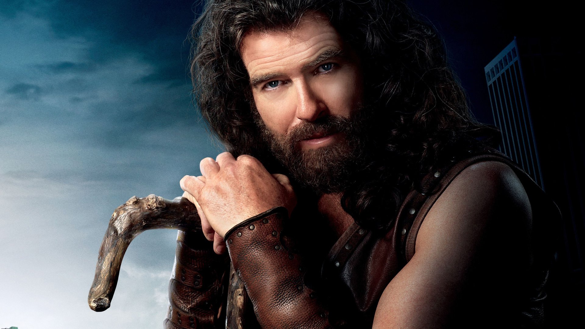 HD PC desktop wallpaper featuring a character from the movie Percy Jackson & the Olympians: The Lightning Thief, with a rugged man holding a staff against a cloudy sky.