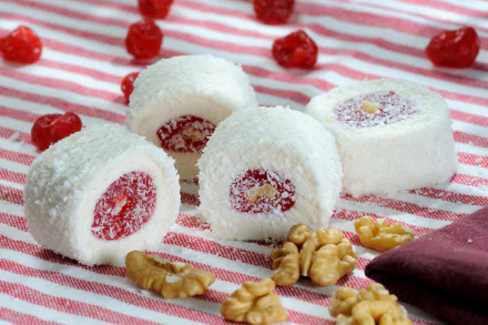 HD PC desktop wallpaper featuring white coconut-covered sweets with red filling, scattered walnuts, and red berries on a striped cloth background.
