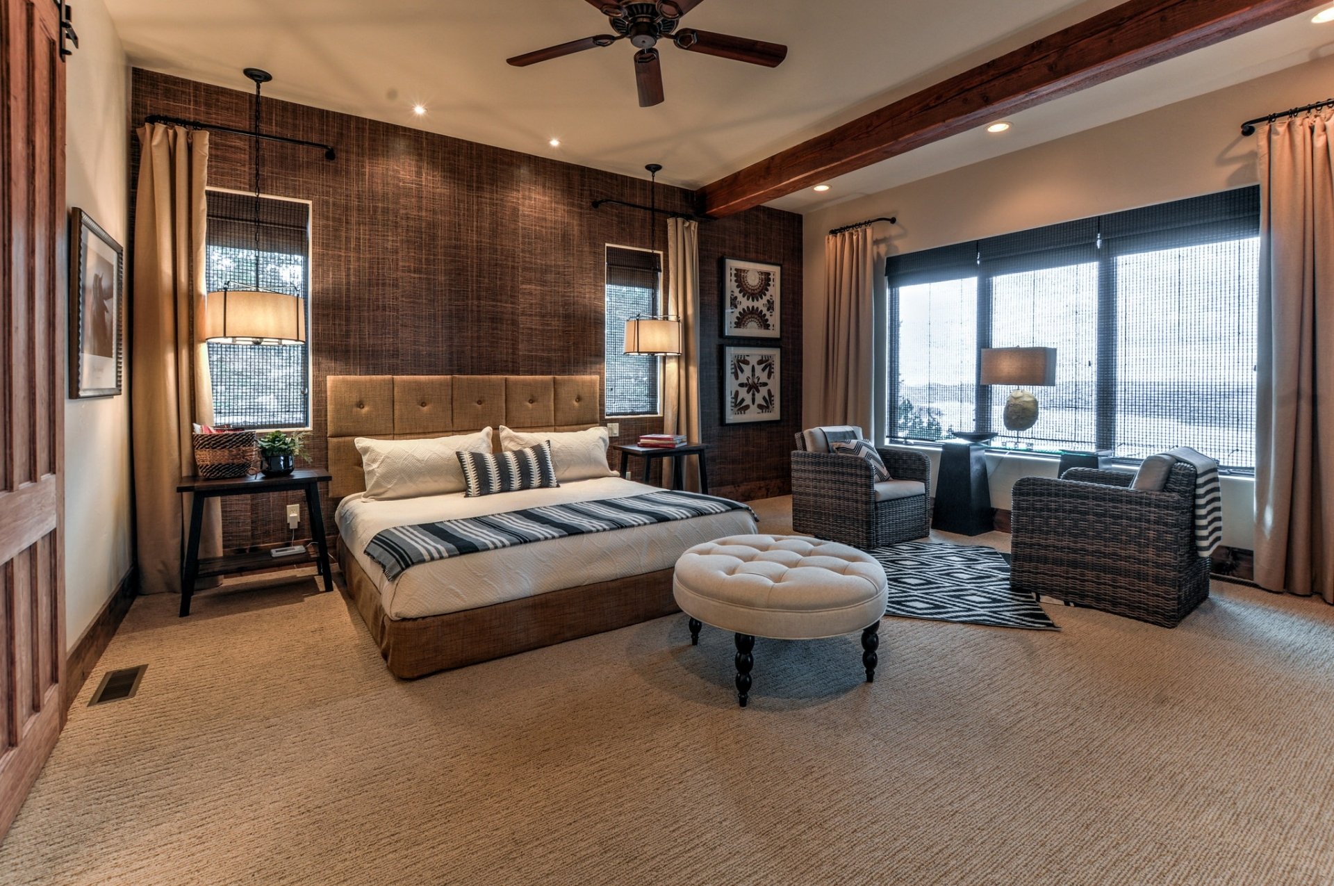 HD desktop wallpaper showcasing a spacious, man-made bedroom with modern furniture, including a bed, seating area, and large windows letting in natural light.