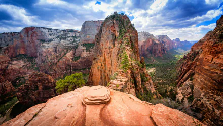 HD image of a breathtaking landscape in Zion National Park, Utah, featuring a stunning red-rock canyon valley surrounded by rugged mountains under a vivid blue sky with scattered clouds.