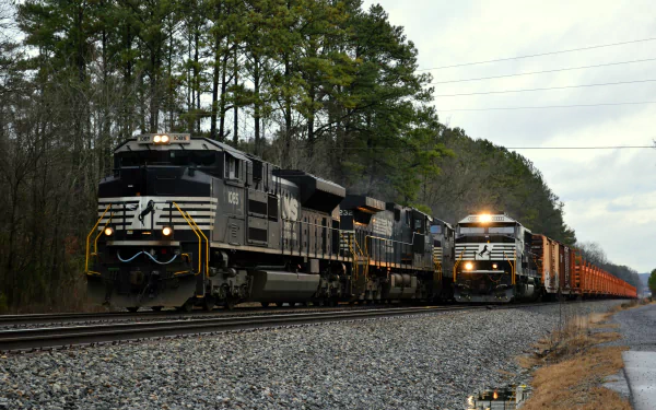 HD desktop wallpaper featuring two trains traveling on parallel tracks through a wooded area under a cloudy sky.