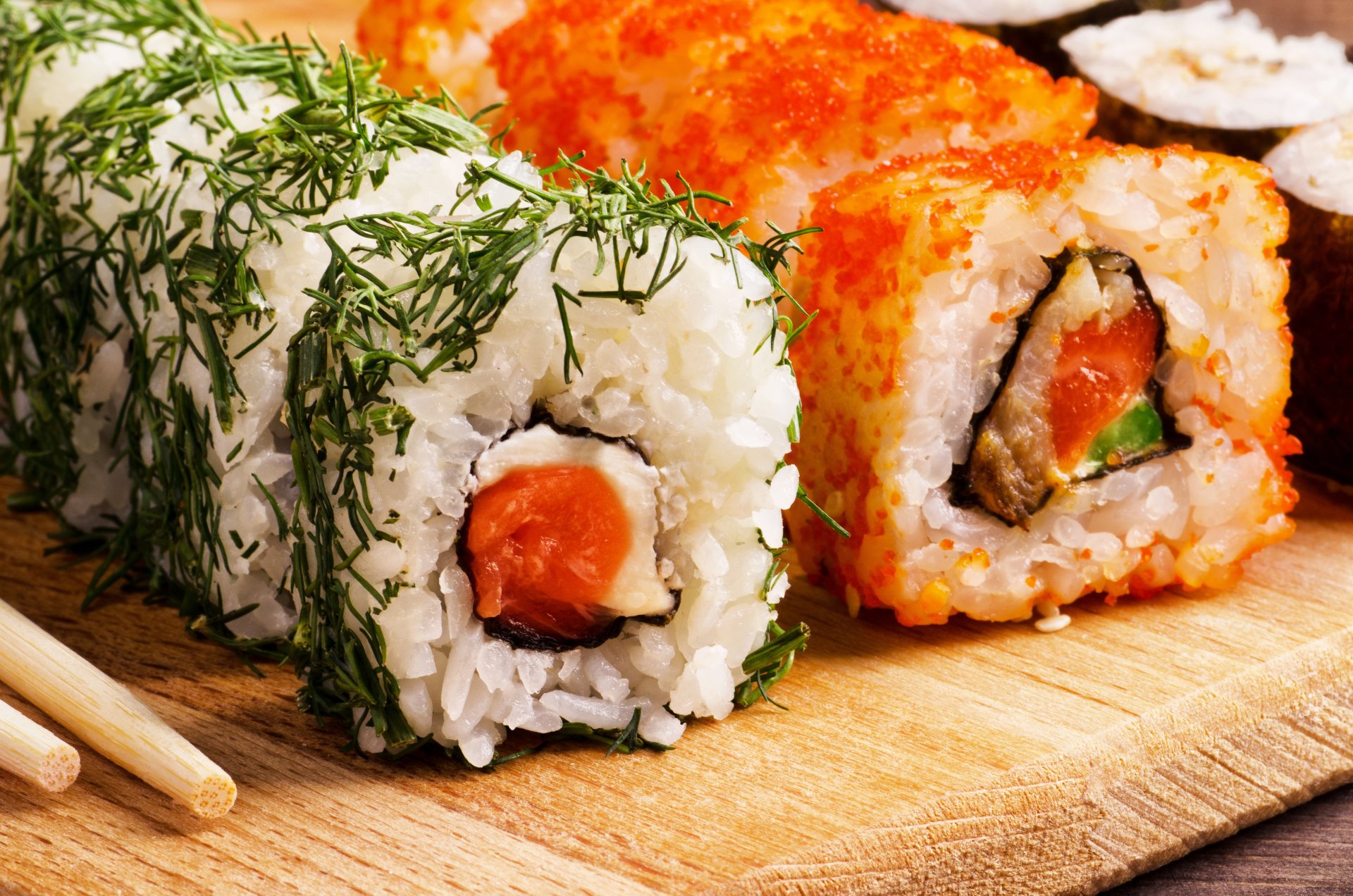 4K Ultra HD PC desktop wallpaper: close-up of assorted sushi rolls—rice, fish and seafood garnished with dill and bright orange roe on a wooden board.