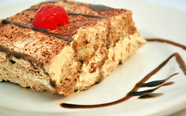 4K Ultra HD PC desktop wallpaper: close-up of a creamy tiramisu-style pastry dessert topped with a cherry and chocolate drizzle on a white plate.