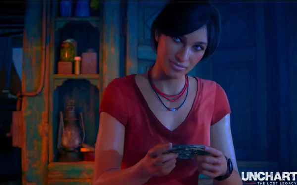HD PC desktop wallpaper from Uncharted: The Lost Legacy showing Chloe Frazer smiling and holding a small object in a dim, warmly lit room; the game's logo appears at the lower right.
