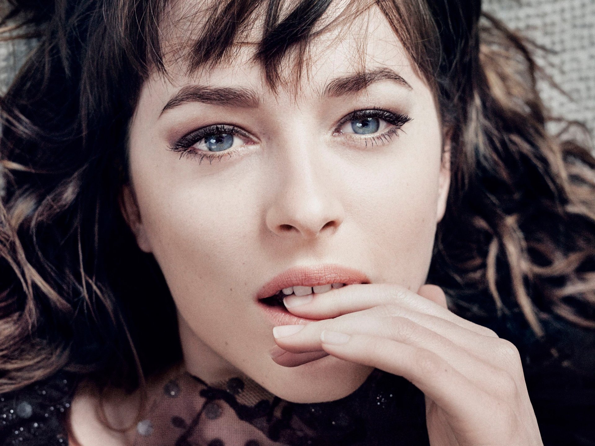 Close-up HD wallpaper of American actress Dakota Johnson with blue eyes and brunette hair, showcasing her expressive face and delicate features.