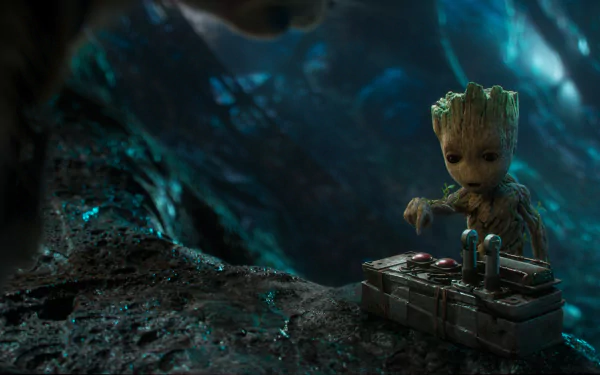 HD desktop wallpaper featuring Groot from the movie Guardians of the Galaxy Vol. 2, standing beside a device in a forest setting.
