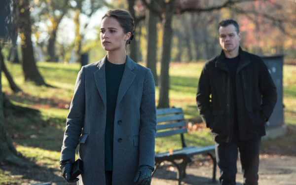 Alicia Vikander and Matt Damon in a scene from the movie Jason Bourne, set in a park with autumn foliage, capturing a tense moment between the two characters.
