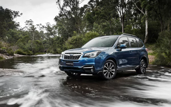 HD desktop wallpaper featuring a blue Subaru Forester SUV parked in a shallow river surrounded by lush green trees and natural scenery.