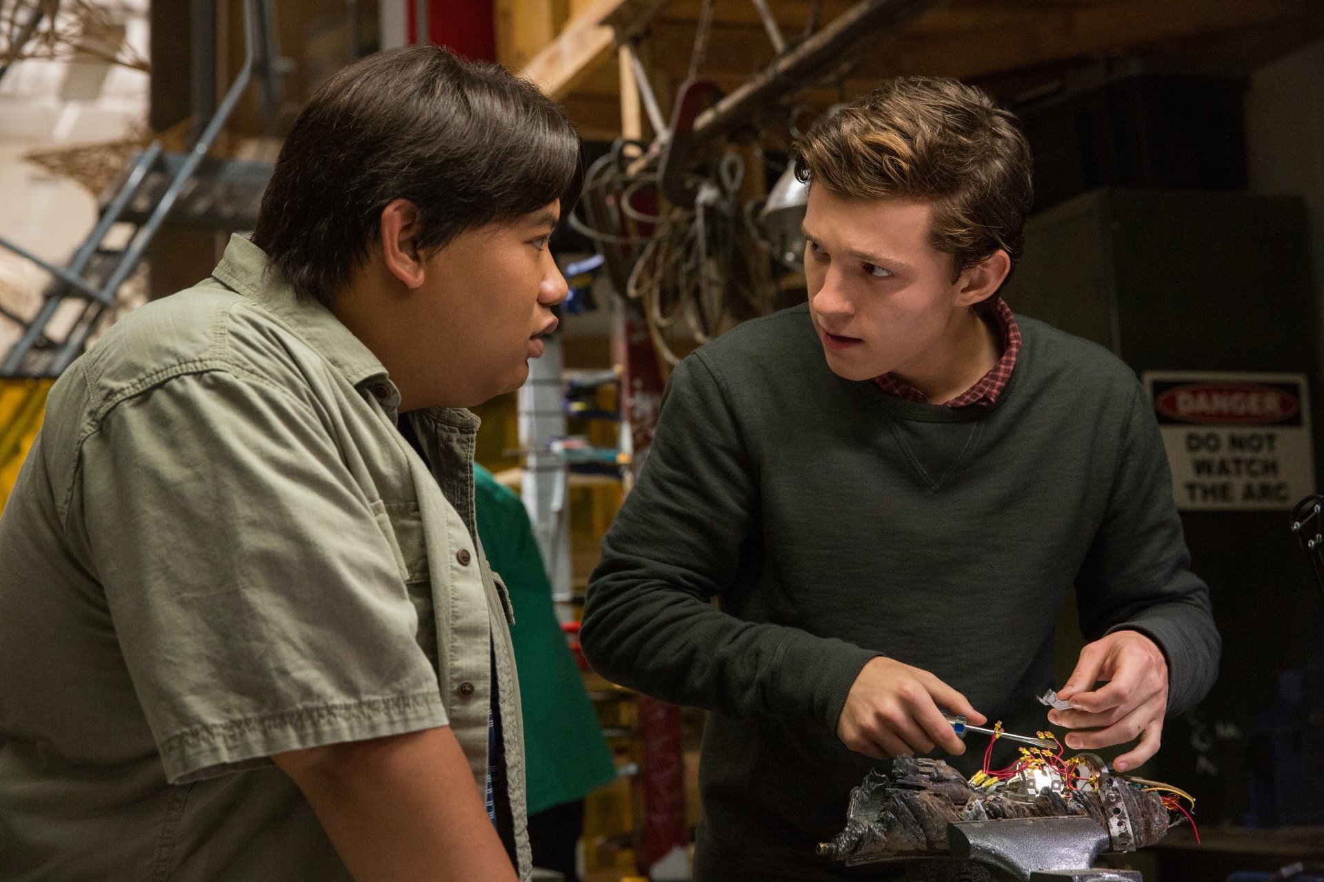 Jacob Batalon and Tom Holland as Peter Parker in a workshop scene from Spider-Man: Homecoming. This HD desktop wallpaper showcases a pivotal moment from the movie.
