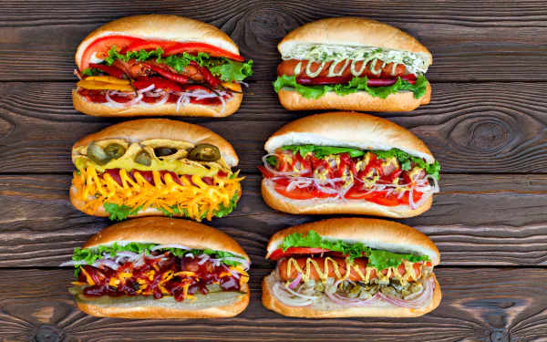 4K Ultra HD PC desktop wallpaper featuring six vibrant hot dogs with various toppings on a wooden background.
