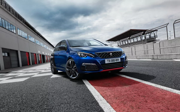 Blue Peugeot 308 car parked on a racetrack pit lane beside garages, framed as a 2K Quad HD PC desktop wallpaper and background.