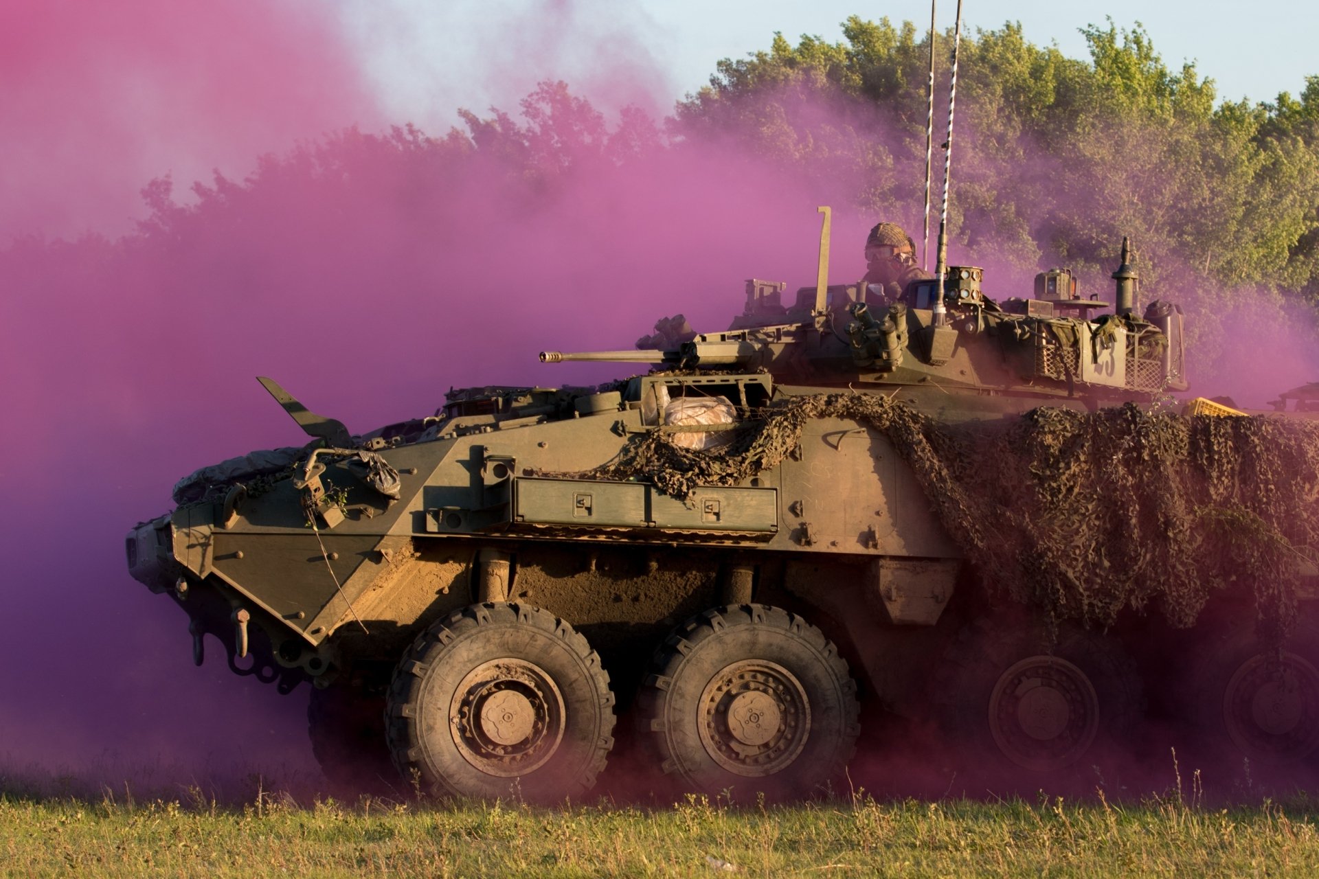 2K Quad HD PC desktop wallpaper background: military armored personnel carrier vehicle advancing through purple smoke over a grassy field.
