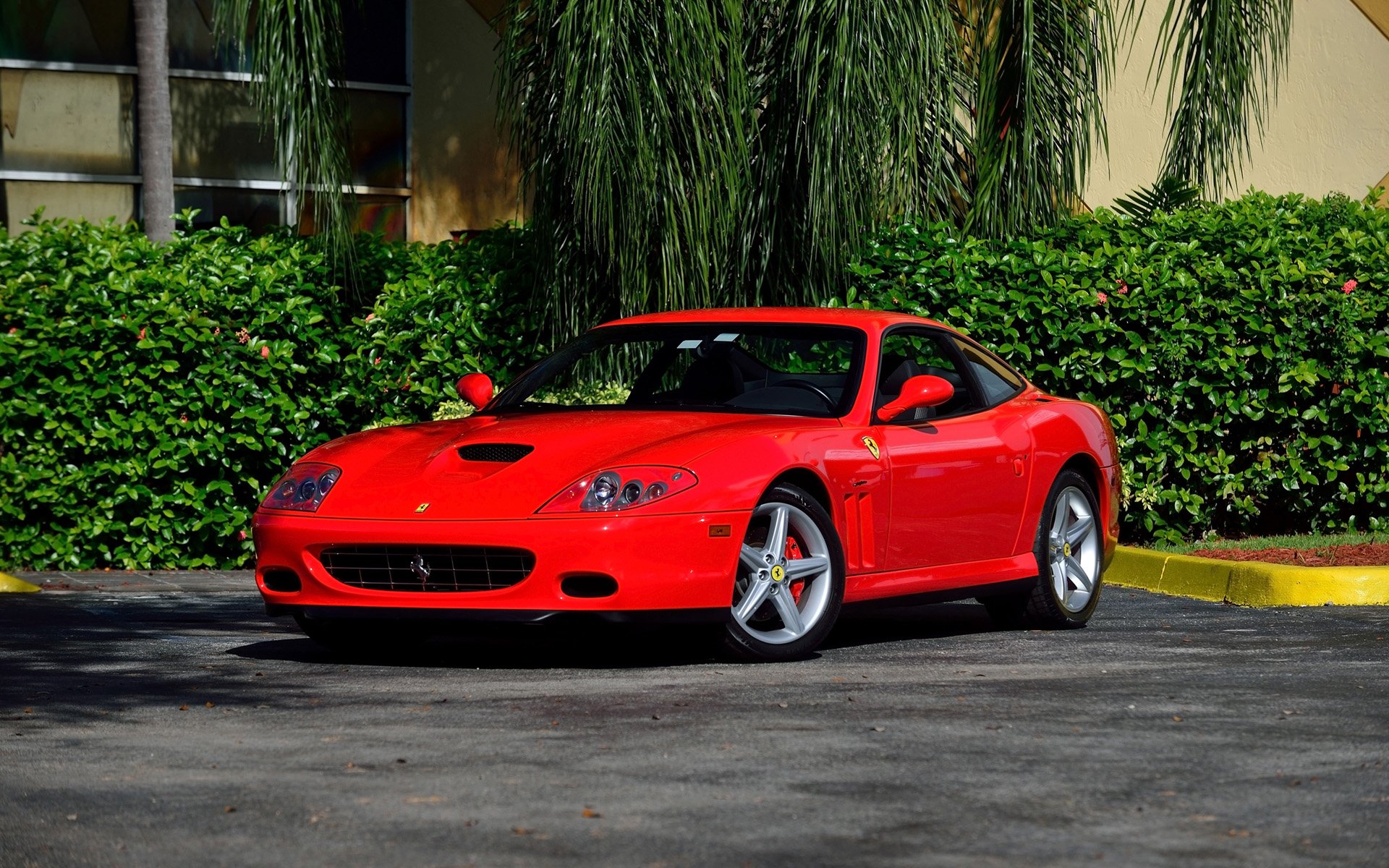 Red Ferrari 575M supercar vehicle parked in front of green hedges, captured as an HD PC desktop wallpaper and background.