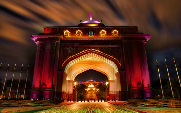 Night-lit man-made palace arch in Abu Dhabi with vivid colored lights and dramatic clouds — 8K Ultra HD PC desktop wallpaper and background.