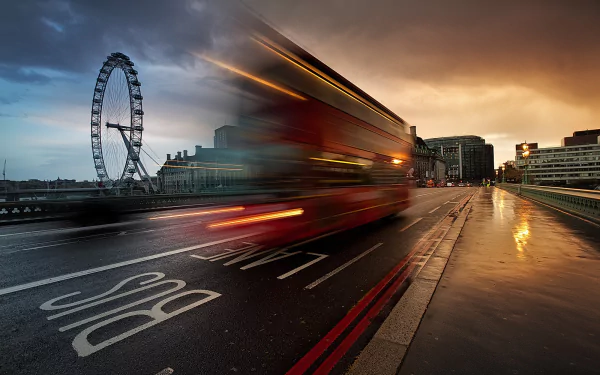 London’s iconic Ferris wheel with a red double-decker bus captured in motion blur on a wet street at dusk, creating a dynamic HD desktop wallpaper scene.