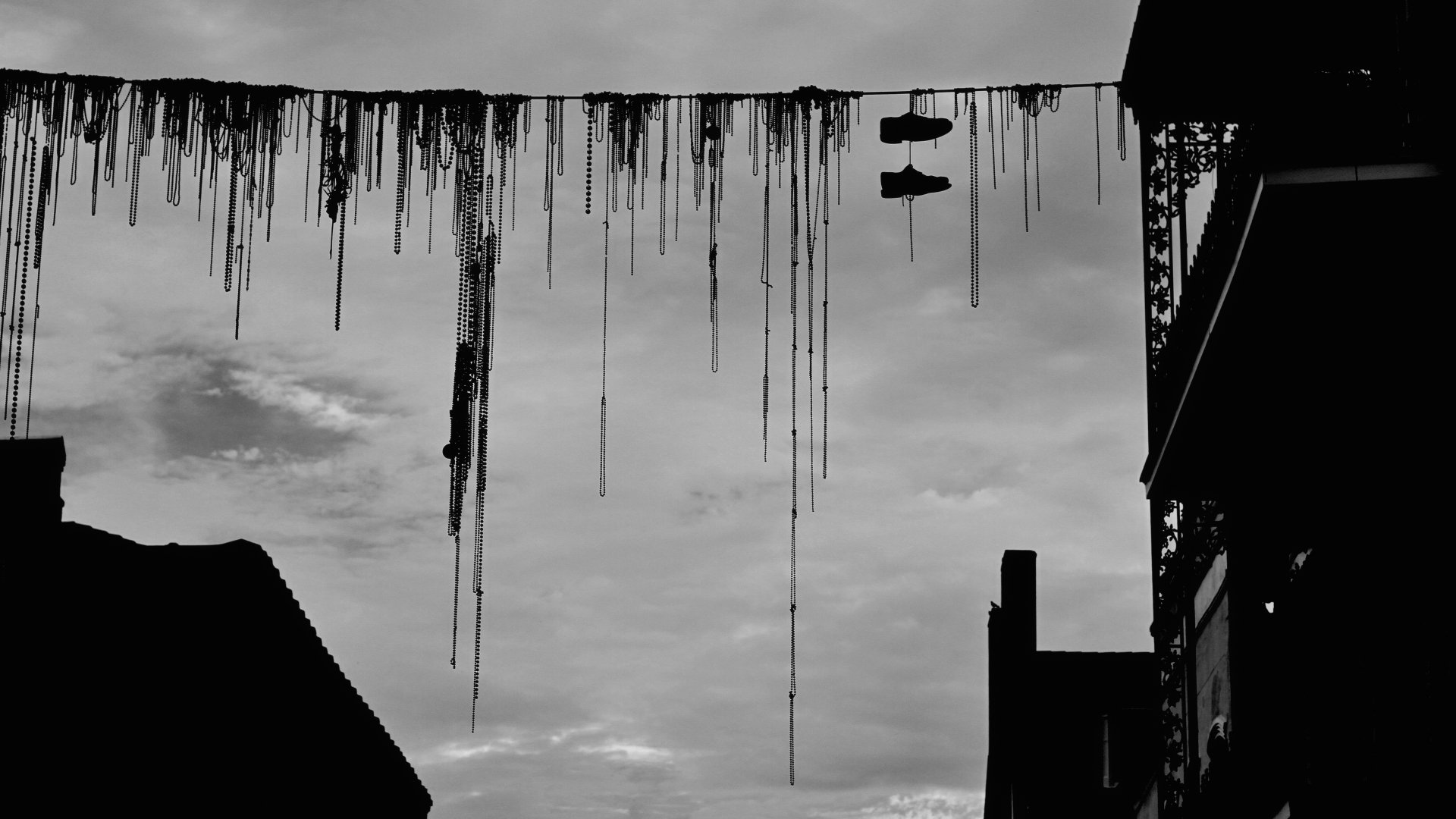 4K Ultra HD PC desktop wallpaper/background: black-and-white favela rooftops and man-made structures silhouetted, with hanging cables and a pair of shoes against a cloudy sky.